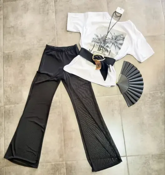 Look con remera blanca estampada, cinto y pantalón wide leg negro